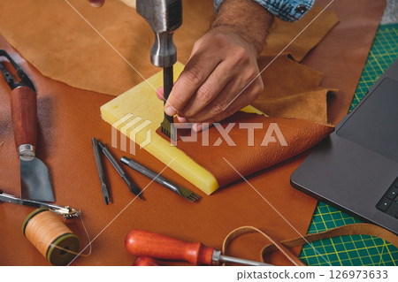 Shoemaker working leather with hammer and punching tool Shoemaker working leather with hammer and punching tool 126973633