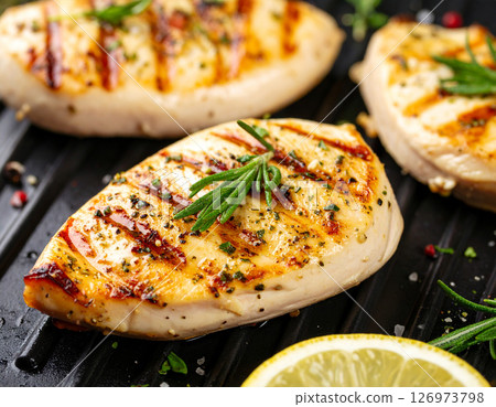 AI generated top view of perfectly grilled chicken steak pieces on charcoal grill, juicy and tender with light smoke. Seasoned with salt and black pepper, garnished with rosemary sprigs. 126973798