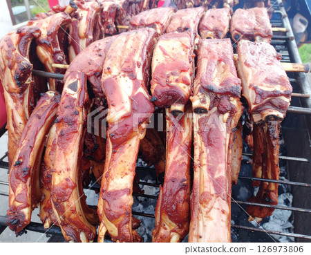 AI generated top view of tender grilled goat meat pieces on charcoal grill, perfectly cooked with light smoke. Seasoned with salt and black pepper, garnished with fresh rosemary. 126973806