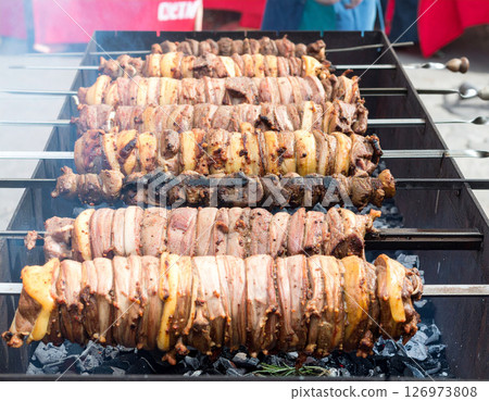 AI generated top view of tender grilled goat meat pieces on charcoal grill, perfectly cooked with light smoke. Seasoned with salt and black pepper, garnished with fresh rosemary. 126973808