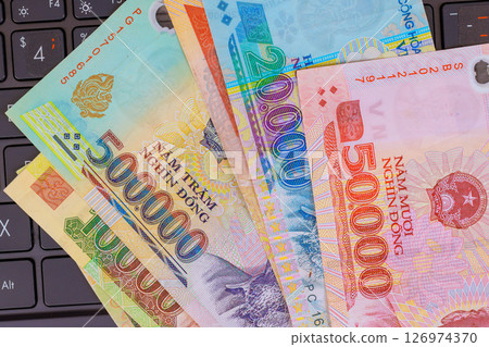 Vietnamese currency dong cash banknotes denominations arranged on laptop keyboard during digital workspace 126974370