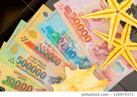 Vietnamese dong banknotes cash are creatively displayed alongside starfish seashell, hinting at travel plans Vietnamese dong banknotes cash are creatively displayed alongside starfish seashell, hinting at travel plans 126974371