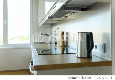 A bright kitchen set with a stylish bouquet in a stylish living room, on the surface there is a pepper shaker, a salt shaker and a kettle 126974421