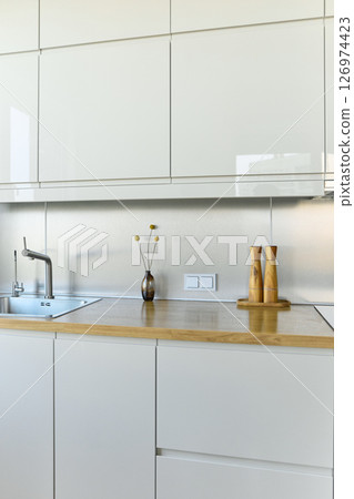 A bright kitchen set with a stylish bouquet in a stylish living room, on the surface there is a pepper shaker, a salt shaker and a kettle 126974423