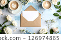 Coffee cups, envelope, blank card, and white flowers on a textured blue background, top view. 126974865