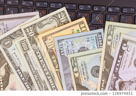 Stack of US dollar bills arranged on laptop keyboard, symbolizing banking, transactions, financial activities. 126974931