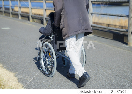 Husband assisting wife in wheelchair 126975061