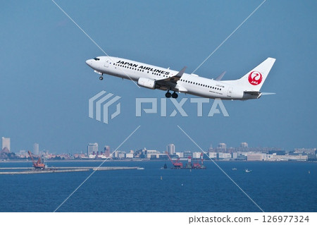 A JAL passenger plane ascends over Tokyo Bay after taking off from runway C at Haneda Airport. 126977324