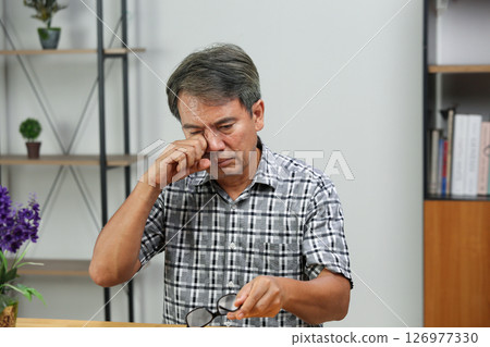 Senior man eye strain after for long stretches at computer or digital screens. 126977330