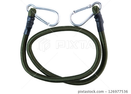 Green bungee cord with metal carabiner hooks at both ends, laid in a circular shape on a white background. Heavy-duty elastic rope for securing gear. 126977536