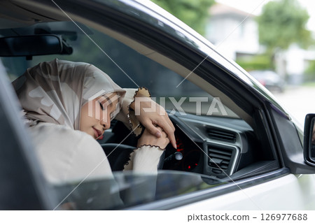 Muslim women sleep inside car on steering wheel. Feeling drowsy while driving. When you feel sleepy, you should stop driving to rest. 126977688