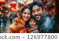 A joyful family celebrates Chinese New Year with radiant smiles, traditional lion dance, and colorful lanterns, cherishing unity, love, and festive traditions in a vibrant street setting. 126977800