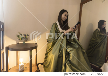 Image of a woman looking at her smartphone while taking a mugwort steam bath 126978270