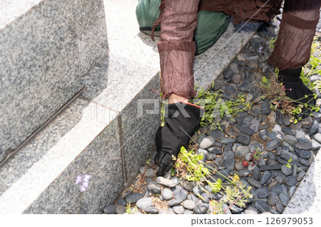 Senior woman weeding a grave 126979053