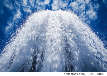 Powerful waterfall cascading from rocky cliffs under a bright blue sky Powerful waterfall cascading from rocky cliffs under a bright blue sky 126980002