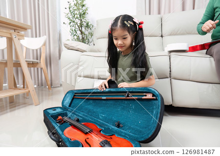 Exploring Music. Young girl opening violin case, excited for her first lesson. Exploring Music. Young girl opening violin case, excited for her first lesson. 126981487