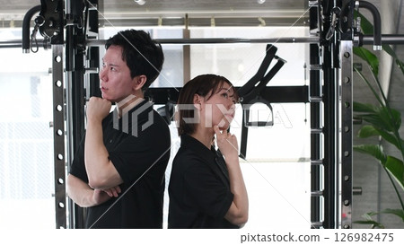Young asian male and female staff struggling back to back in sports gym Young asian male and female staff struggling back to back in sports gym 126982475