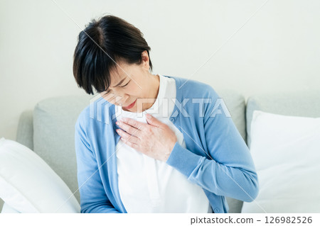 中年婦女坐在沙發上，雙手放在胸前 126982526