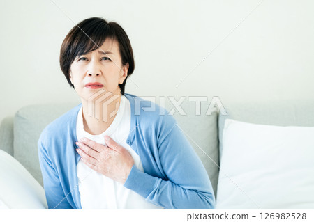 中年婦女坐在沙發上，雙手放在胸前 126982528