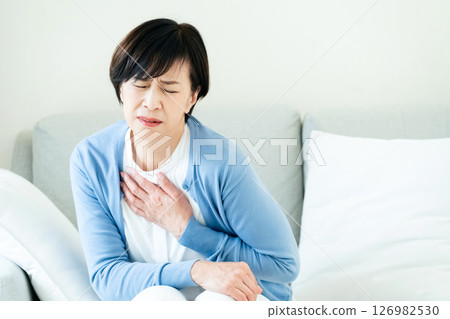 Middle-aged woman sitting on sofa with hands on chest 126982530