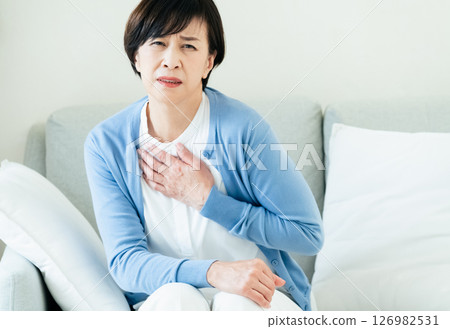 中年婦女坐在沙發上，雙手放在胸前 126982531