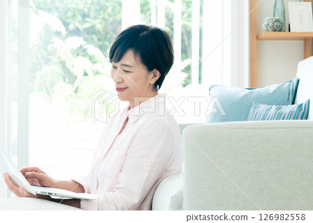 A middle-aged woman operating a computer in the living room 126982558
