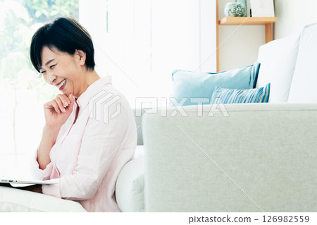 A middle-aged woman operating a computer in the living room 126982559