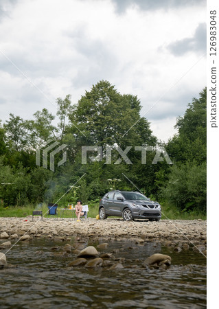 Camping by the River with SUV and Campfire 126983048
