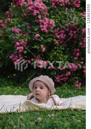 Child Lying on Blanket Surrounded by Pink Flowers 126983050