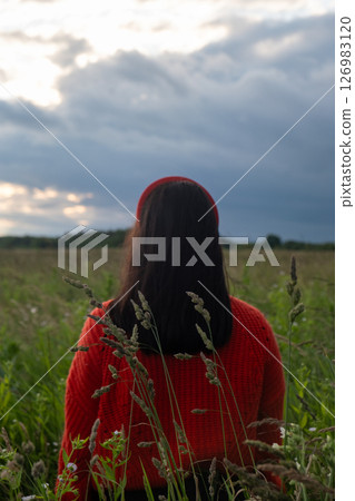 Woman in Red Sweater in Grassy Field Woman in Red Sweater in Grassy Field 126983120