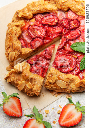 Delicious homemade strawberry galette with almond petals baking on parchment paper 126983706