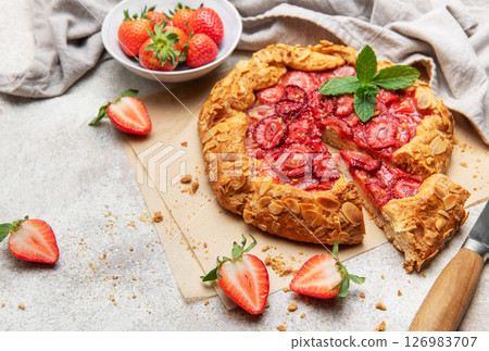 Delicious homemade strawberry galette with almond petals baking on parchment paper 126983707