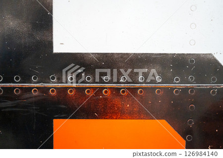 Close-up of riveted orange and white aircraft fuselage with glossy paint 126984140