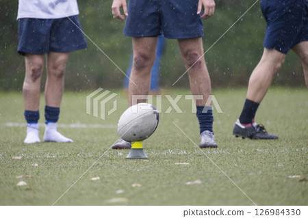 Rugby players preparing for kicking practice under rain 126984330