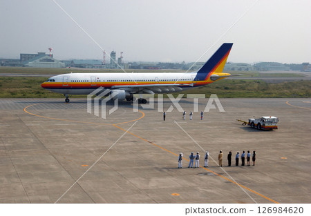 Ground staff waving to a departing plane 126984620