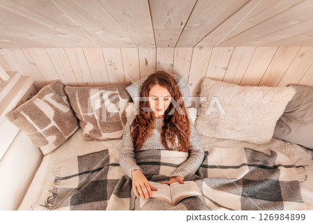 Woman Enjoying Cozy Winter Reading in Bed 126984899