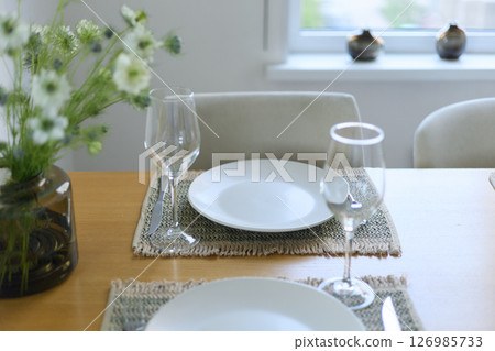 a bouquet of daisies in a glass vase stands on a table on a white background, a wine glass, table setting, plates, defocus, macrophotography, bokeh a bouquet of daisies in a glass vase stands on a table on a white background, a wine glass, table setting, plates, defocus, macrophotography, bokeh 126985733