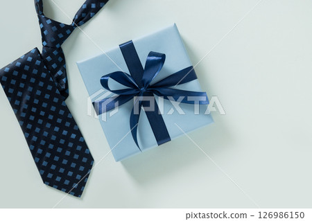 Happy Fathers Day gift box and tie on pastel blue background. Creative concept with mens accessories. Flat lay. View from above. Copy space. Happy Fathers Day gift box and tie on pastel blue background. Creative concept with mens accessories. Flat lay. View from above. Copy space. 126986150