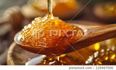 Honey drips onto a wooden spoon. 126987006