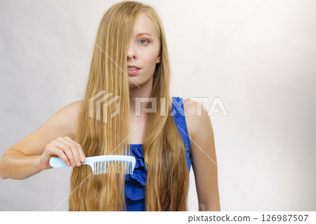 Woman combing long healthy blonde hair Woman combing long healthy blonde hair 126987507