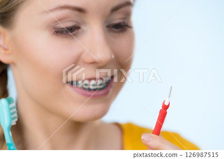 Woman smiling cleaning teeth with braces Woman smiling cleaning teeth with braces 126987515