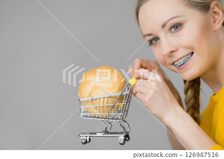 Woman holding shopping cart with bread Woman holding shopping cart with bread 126987516