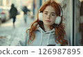 Portrait of a red-haired woman in white headphones 126987895