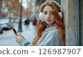 Beautiful young woman in white headphones with red hair. 126987907