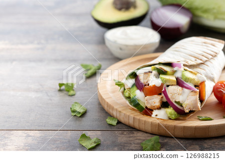 A delicious grilled chicken wrap with vegetables and avocado A delicious grilled chicken wrap with vegetables and avocado 126988215