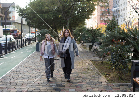 Autumn walk. Daughter and mother walking outdoors Autumn walk. Daughter and mother walking outdoors 126989824