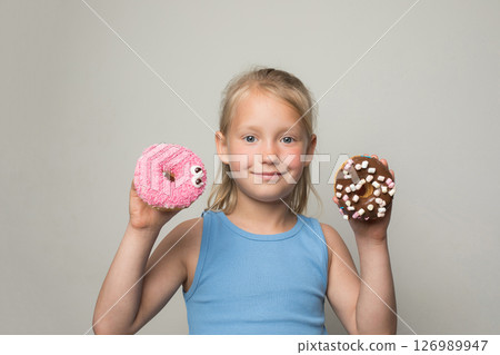 Pretty child girl holding testy donut. Cute little girl with sweet food indoor Pretty child girl holding testy donut. Cute little girl with sweet food indoor 126989947