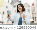 Real talk. Indian woman in a white casual shirt and short hair on a video call with family against a backdrop of urban motion 126990044