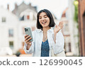 Face time. Latina woman with short hair and a casual white shirt chats with loved ones while handling banking tasks on mobile 126990045