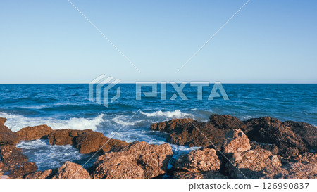 Sea stones on the background of the ocean and the blue boundless ocean. Ocean pattern for the background. 126990837